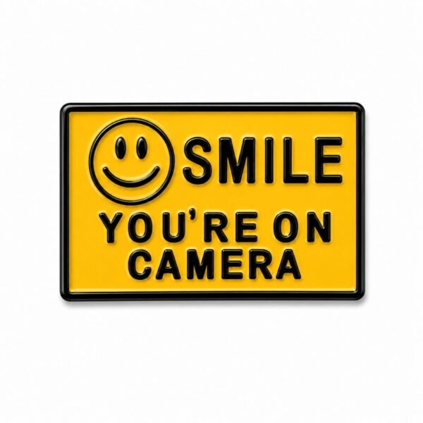 ستيكر معدني أصفر بتصميم Smile You're on Camera مع أيقونة الوجه المبتسم.