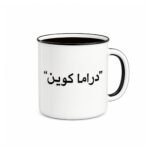 كوب أبيض مطبوع عليه عبارة دراما كوين باللون الأسود.